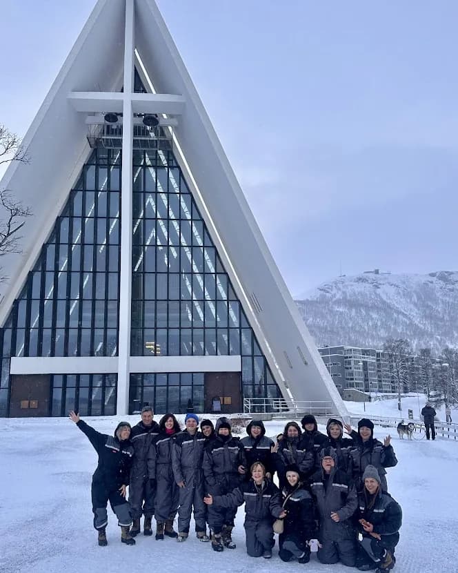 Grupo de viajantes da Paralelo 30 diante de uma catedral moderna em paisagem de neve